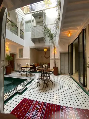 a living room with a pool and tables in a building at Riad Magnolia&SPA in Marrakech