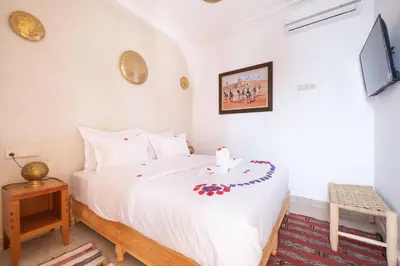 a bedroom with a large white bed and a tv at Riad El Habib in Marrakech