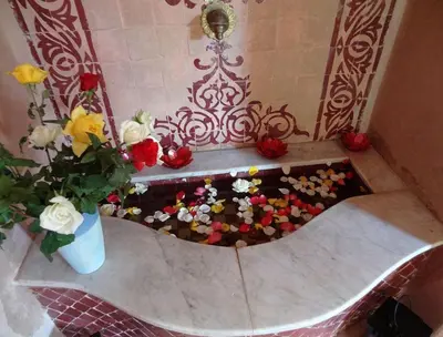 a bathtub filled with flowers and a vase of roses at Villa Aalama in Marrakech