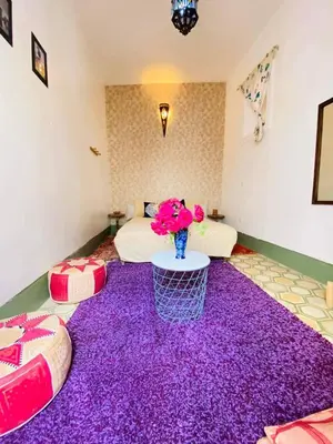 a room with a purple carpet with a bed and a vase of flowers at house rose in Marrakech