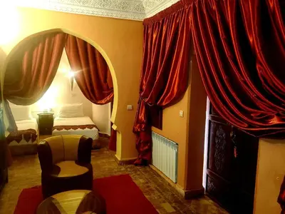 a living room with a bed and red curtains at Riad Rêve d Antan , Real Dream in Marrakech