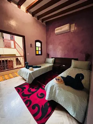 a bedroom with two beds and a red carpet at RIAD ZAKARYA in Marrakech