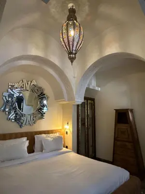 a bedroom with a large bed and a chandelier at Riad Palais Didier Six in Marrakech