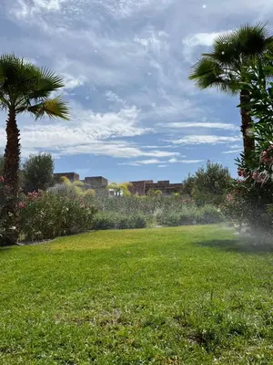 a field of grass with palm trees in the background at Appartement de Luxe -Prestigia Marrakech Golf City in Marrakech