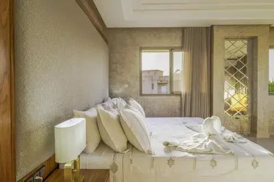 a bedroom with a bed with white sheets and pillows at Villa Naciri en plein golf avec vue sur Atlas in Marrakech