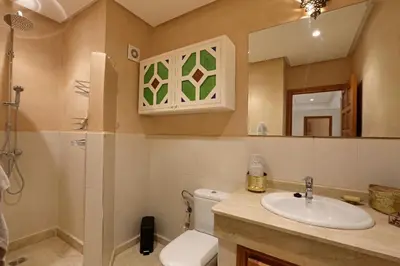 a bathroom with a sink and a toilet and a mirror at Appartement moderne en City Center Marrakech-Gueliz in Marrakech