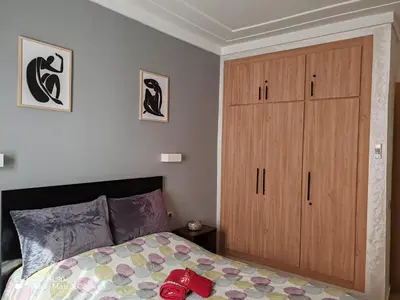 a bedroom with a bed and a wooden cabinet at Résidence NAJD C - Appartement T2 in Marrakech
