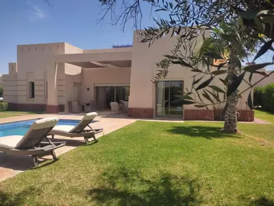 a house with two lounge chairs and a swimming pool at Villa isolée 4 façades avec piscine in Marrakech