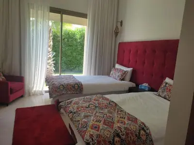 a hotel room with two beds and a window at Villa isolée 4 façades avec piscine in Marrakech