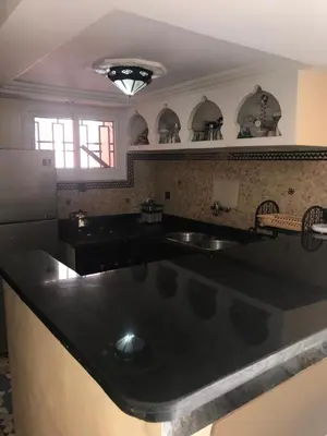 a kitchen with a black counter top and a refrigerator at Riad Syrine in Marrakech