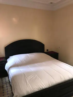 a bedroom with a white bed with a black headboard at Riad Syrine in Marrakech