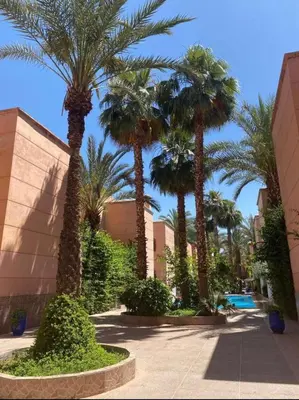 a group of palm trees in front of a building at Riad Syrine in Marrakech