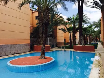 a swimming pool with palm trees in a resort at Riad Syrine in Marrakech