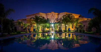 a large building with a pool in front of it at night at Las Palmeras Guest House in Marrakech