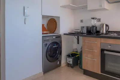 a kitchen with a washing machine in a kitchen at Prestigia, superbe appartement, vue sur golf, piscine et Atlas in Marrakech