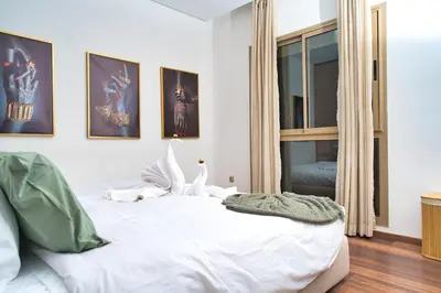 a bedroom with a bed with white sheets and a window at Prestigia, superbe appartement, vue sur golf, piscine et Atlas in Marrakech