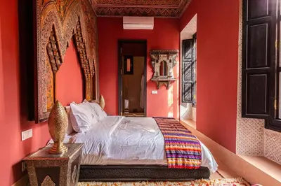 a bedroom with red walls and a bed with a mirror at Palais El Roucar in Marrakech