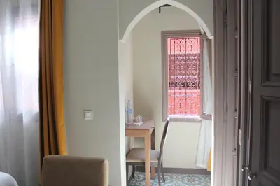 a room with a chair and a table and a window at Riad Hilmuna Hammam et Spa in Marrakech