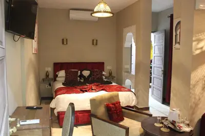 a bedroom with a large bed and a tv at Riad Hilmuna Hammam et Spa in Marrakech