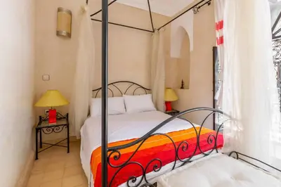 a bedroom with a bed with a metal canopy at Riad les épices in Marrakech