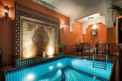 a swimming pool in a building with an ornate wall at Riad Mounlight in Marrakech