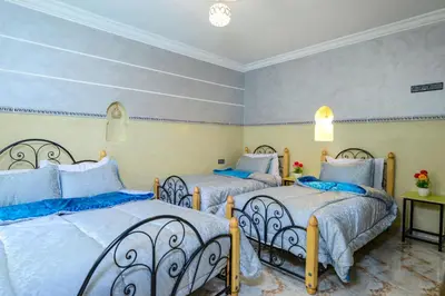 a bedroom with two beds with blue pillows at Hôtel Faouzi in Marrakech