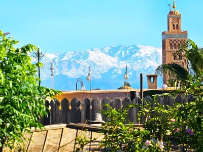 a church with a clock tower with mountains in the background at Riad Jnane d'Ô in Marrakech