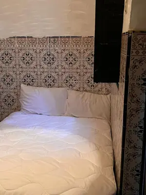 a bed with white sheets and a patterned head board at Riad TaTam House in Marrakech