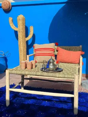 a rattan bench with pillows and a table with at Riad Sofia signature in Marrakech