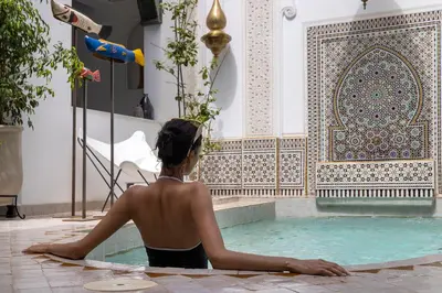 a woman sitting in a swimming pool in a building at Riad LAZ Mimoun & Spa in Marrakech