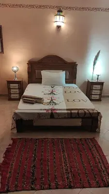 a bedroom with a large bed with a red rug at Maison style riad aux chants des oiseaux in Marrakech