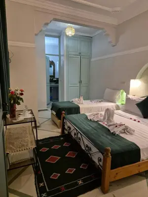 a bedroom with two beds and a table and a mirror at Dar 