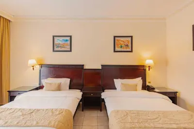 a hotel room with two beds and two tables at Grand Mogador Agdal & Spa in Marrakech