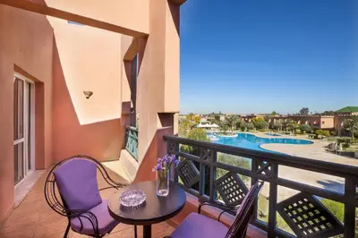 a balcony with a table and chairs and a pool at Grand Mogador Agdal & Spa in Marrakech