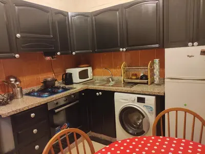 a kitchen with black cabinets and a washing machine at Appartement dans résidence avec piscine in Marrakech