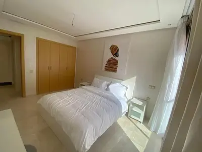 a bedroom with a white bed and a window at APPARTEMENT CARRE EDEN in Marrakech