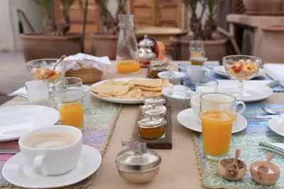 a table with plates of food and glasses of orange juice at Riad Al Massarah in Marrakech