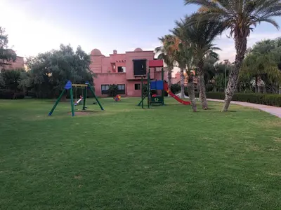 a park with a swing set and palm trees at Chez balqis atlas golf in Marrakech