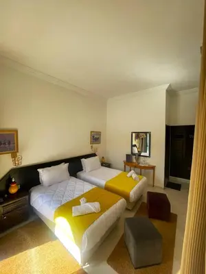 a large bedroom with two beds and a table at Majorel Perle Hôtel Riad Restaurant Picine & Spa in Marrakech
