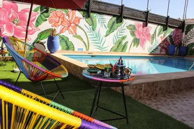 a pool with chairs and a table with drinks on it at Majorel Perle Hôtel Riad Restaurant Picine & Spa in Marrakech