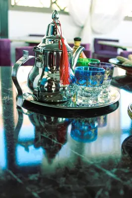 a glass tea kettle and two glasses on a table at Majorel Perle Hôtel Riad Restaurant Picine & Spa in Marrakech