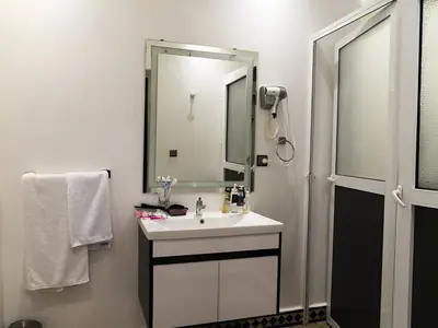 a white bathroom with a sink and a mirror at RIAD DOUIRTNA in Marrakech
