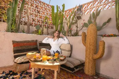 a woman sitting on a couch next to a cactus at Riad Arabkech in Marrakech
