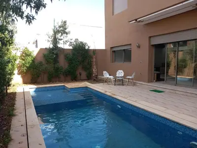 a swimming pool with two chairs next to a house at villa with private pool only family in Marrakech