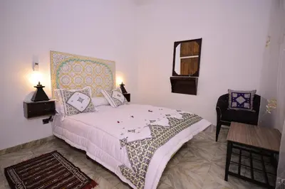 a bedroom with a bed and a table and a chair at RYAD RDATE LWALIDINE in Marrakech