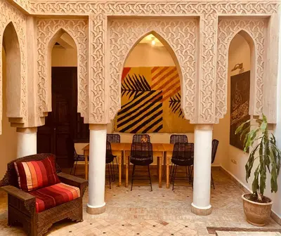 a dining room with a table and chairs and a couch at Riad Laksiba in Marrakech