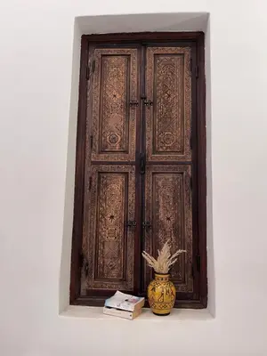 a wooden door with a vase in front of a window at Riad Laksiba in Marrakech