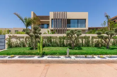 a building with trees and plants in front of it at Villa Nounja Golf Amelkis Marrakech in Marrakech