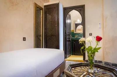a bedroom with a bed and a vase with a flower at Riad Mazaj in Marrakech