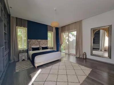 a bedroom with a bed and blue walls and windows at Villa Le Clos de l'Atlas in Marrakech